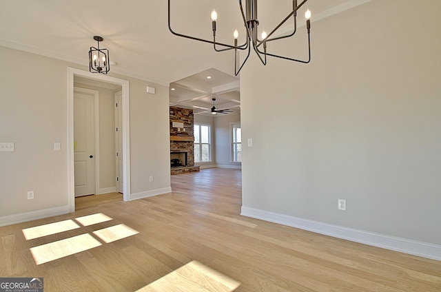 unfurnished dining area featuring beam ceiling, a stone fireplace, light wood-type flooring, coffered ceiling, and baseboards