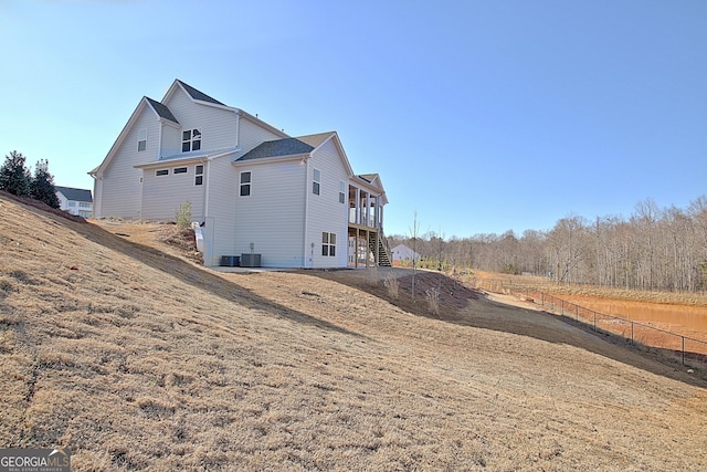 view of side of property with stairway, cooling unit, a wooden deck, and fence