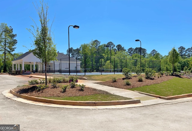 view of home's community featuring a tennis court and fence