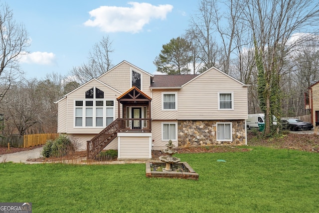 view of front of house with stone siding, fence, and a front lawn