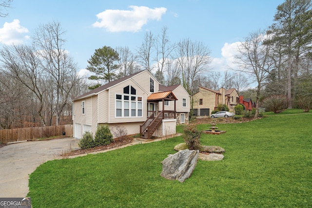 view of front of property with an attached garage, fence, concrete driveway, and a front yard