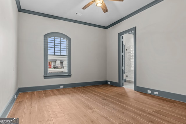 empty room featuring light wood finished floors, visible vents, baseboards, a ceiling fan, and ornamental molding