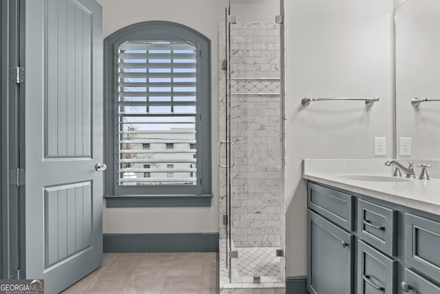 full bathroom with a stall shower, tile patterned flooring, vanity, and baseboards