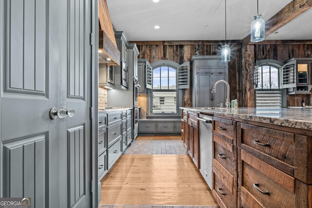 kitchen with gray cabinetry, stainless steel appliances, a sink, light wood finished floors, and pendant lighting