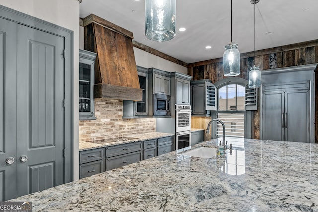 kitchen featuring light stone counters, stainless steel microwave, gray cabinets, black electric cooktop, and a sink