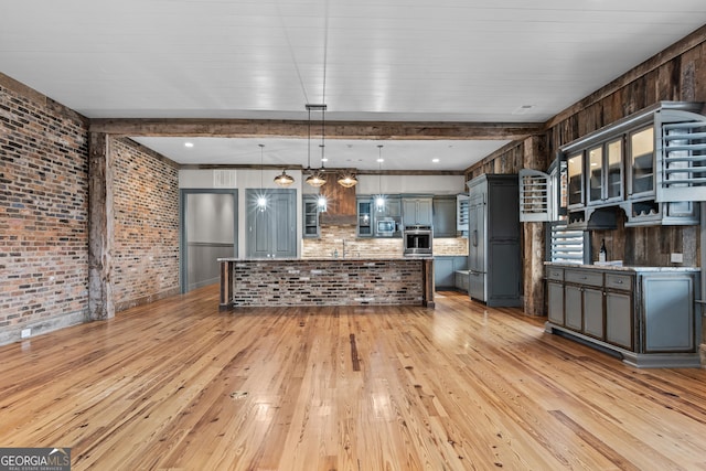 kitchen featuring appliances with stainless steel finishes, light wood finished floors, and brick wall