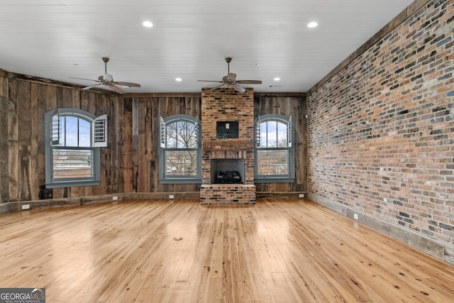 unfurnished living room with brick wall, hardwood / wood-style floors, a fireplace, and recessed lighting