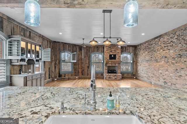 kitchen with glass insert cabinets, a brick fireplace, a sink, and brick wall