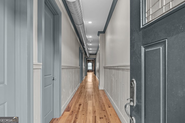 hallway with a wainscoted wall, recessed lighting, and light wood-style floors