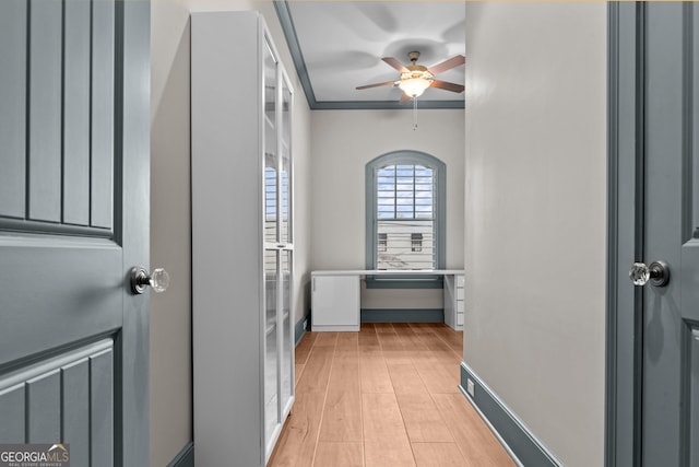 hallway featuring ornamental molding, light wood finished floors, and baseboards