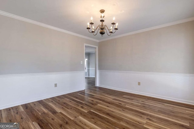 spare room with dark wood-style floors, a wainscoted wall, a notable chandelier, and ornamental molding