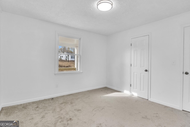 spare room with carpet, a textured ceiling, and baseboards