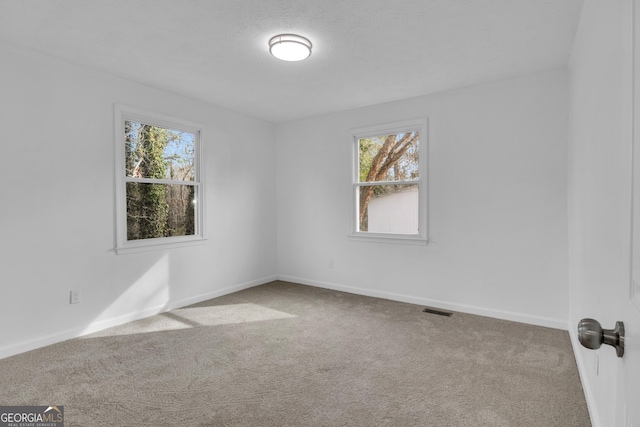 empty room with a textured ceiling, carpet floors, visible vents, and baseboards