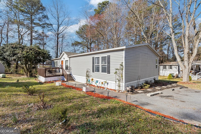 manufactured / mobile home featuring a front lawn and a wooden deck