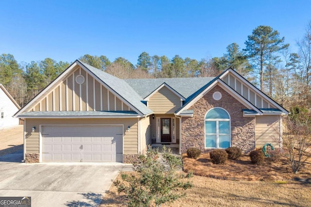 craftsman-style home with roof with shingles, concrete driveway, board and batten siding, a garage, and stone siding