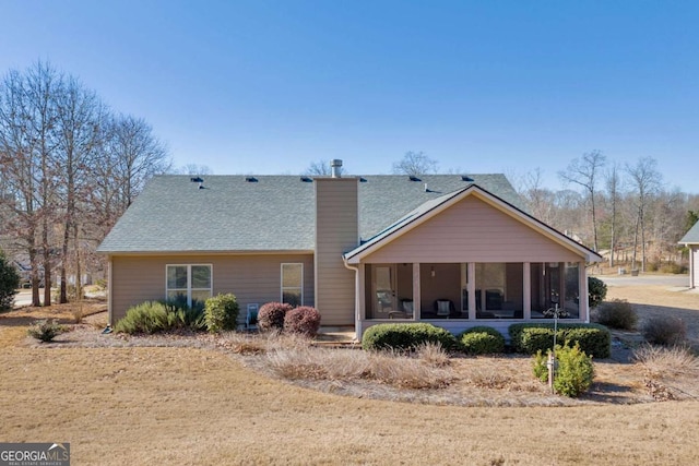 back of property featuring a shingled roof, a chimney, and a sunroom