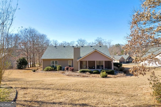 back of property with a yard, a chimney, and a sunroom