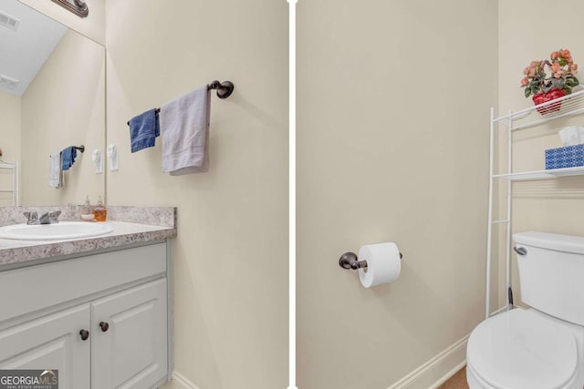 bathroom featuring toilet, baseboards, visible vents, and vanity