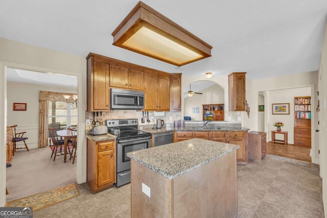 kitchen with stainless steel appliances, arched walkways, backsplash, and light stone counters