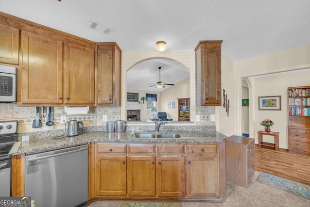 kitchen featuring arched walkways, visible vents, appliances with stainless steel finishes, a sink, and light stone countertops