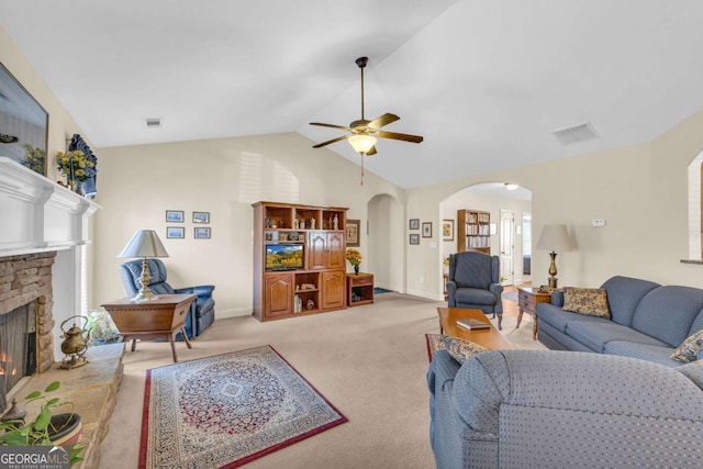 living area featuring arched walkways, a stone fireplace, light carpet, visible vents, and vaulted ceiling