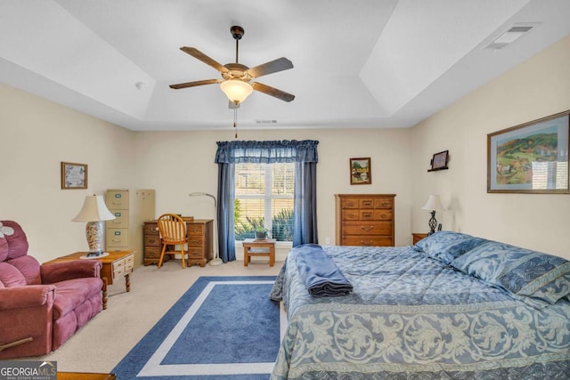 bedroom with carpet, a raised ceiling, visible vents, and a ceiling fan