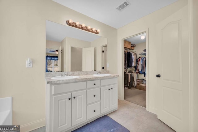 full bath featuring a spacious closet, double vanity, a sink, and visible vents