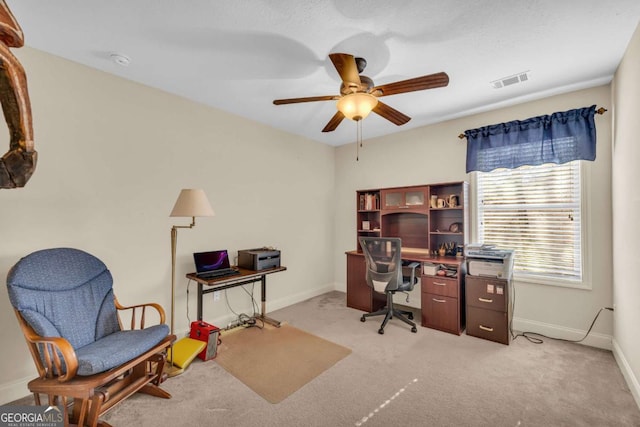 office space with light colored carpet, visible vents, ceiling fan, and baseboards