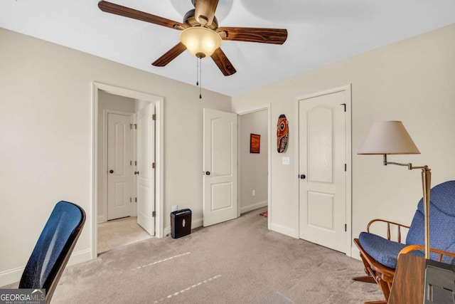 living area featuring ceiling fan, baseboards, and light colored carpet