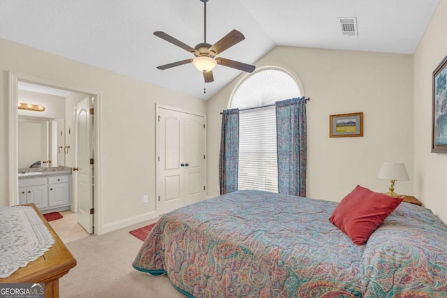 bedroom featuring visible vents, a ceiling fan, light colored carpet, ensuite bathroom, and vaulted ceiling