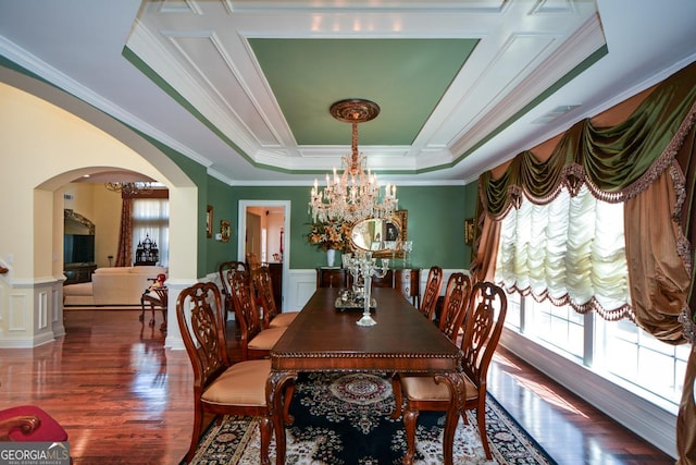 dining room featuring arched walkways, a raised ceiling, wainscoting, and a notable chandelier