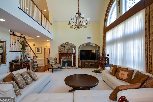 living area with ornamental molding, a fireplace with raised hearth, a notable chandelier, and stairs