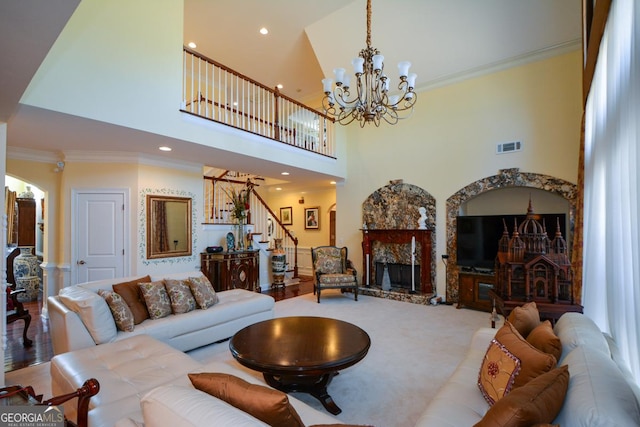 living room featuring visible vents, a premium fireplace, ornamental molding, a chandelier, and stairs