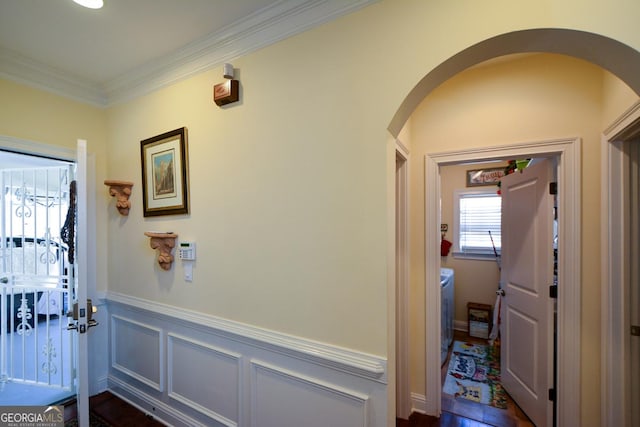 interior space with a wainscoted wall, arched walkways, a decorative wall, and crown molding