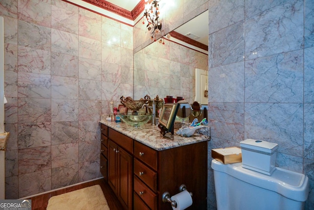 half bathroom with toilet, visible vents, tile walls, and vanity