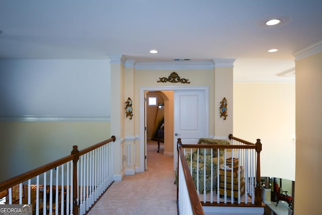 hall featuring visible vents, arched walkways, light colored carpet, ornamental molding, and an upstairs landing