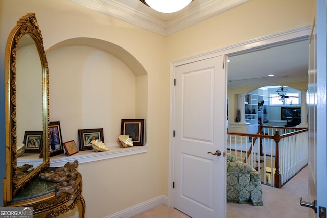 hallway with ornamental molding, baseboards, light colored carpet, and an upstairs landing