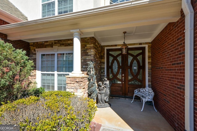 property entrance with stone siding, french doors, covered porch, and brick siding