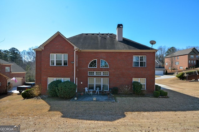 rear view of house featuring a patio area, a chimney, and brick siding