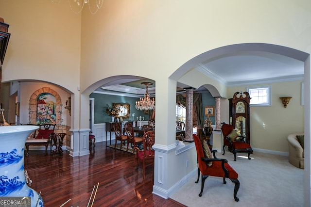 foyer featuring a wainscoted wall, a notable chandelier, arched walkways, and crown molding