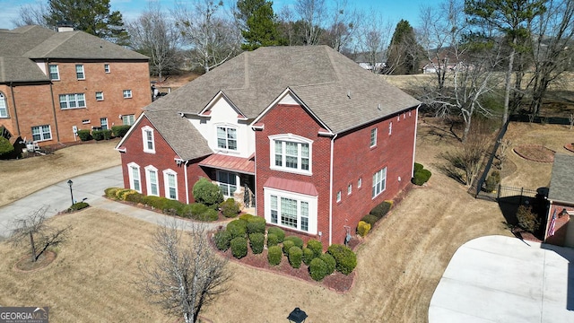 view of front facade featuring driveway, roof with shingles, and brick siding