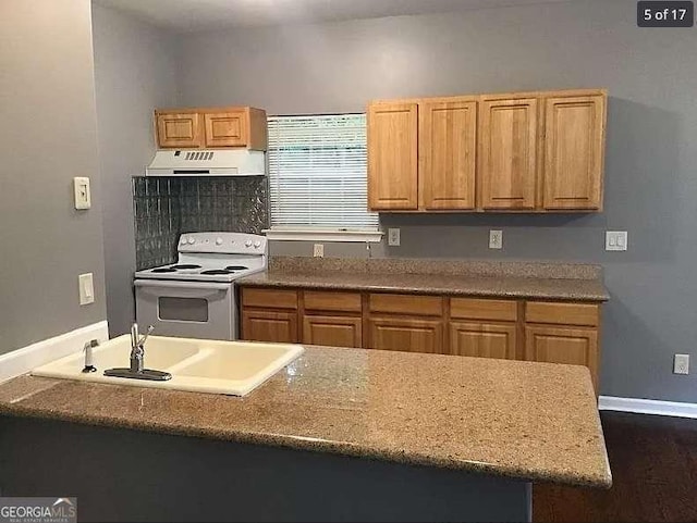 kitchen with under cabinet range hood, electric range, a sink, baseboards, and light countertops