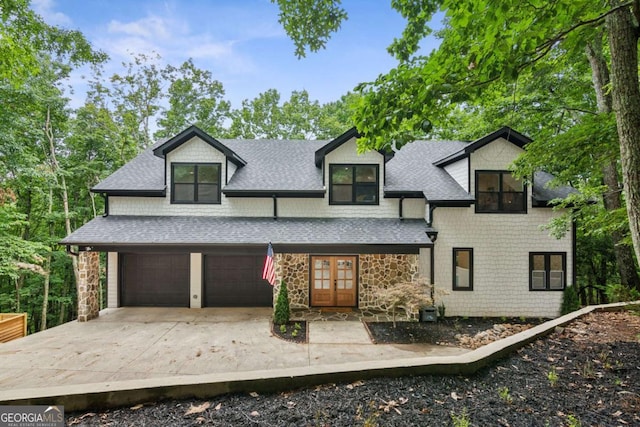 view of front of home featuring a garage, stone siding, roof with shingles, and concrete driveway