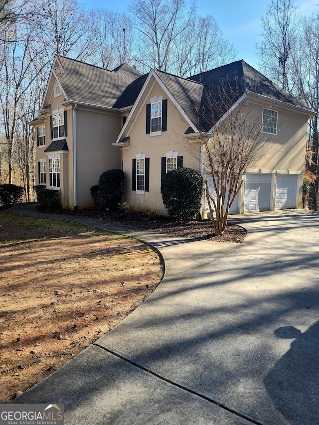 view of front of house with a garage, concrete driveway, and stucco siding