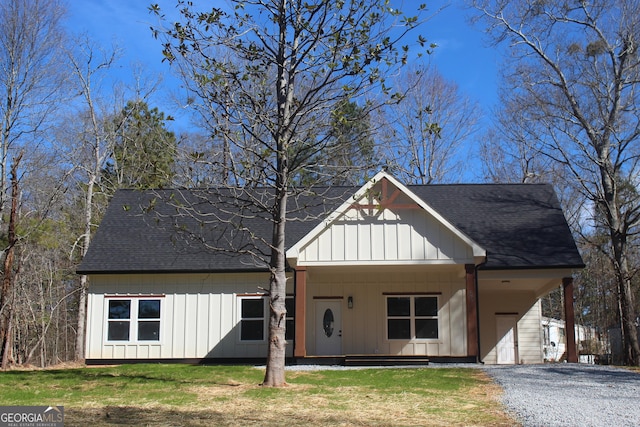 modern inspired farmhouse with board and batten siding, a front yard, a shingled roof, and driveway