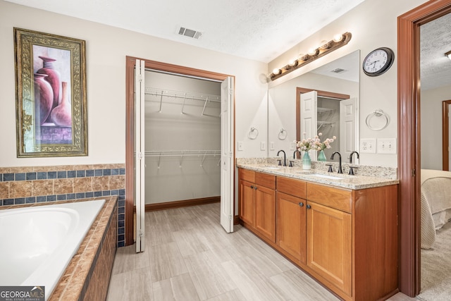full bath featuring double vanity, a textured ceiling, and a sink