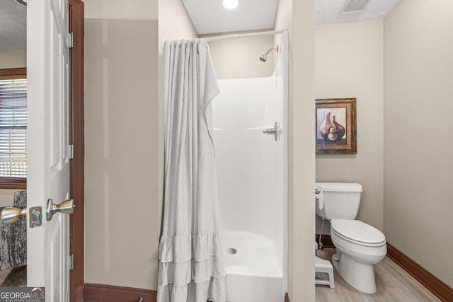 bathroom featuring a textured ceiling, a shower stall, and toilet