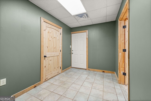 spare room featuring a paneled ceiling, light tile patterned floors, baseboards, and visible vents