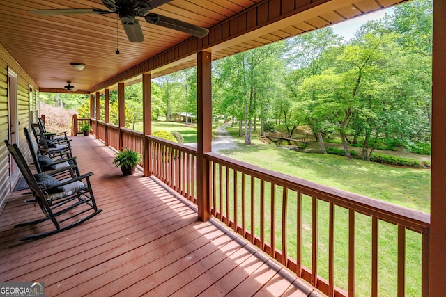 deck featuring ceiling fan, a yard, and a porch