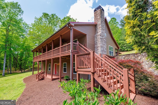 rear view of house with a yard, a chimney, a patio, stairway, and a wooden deck